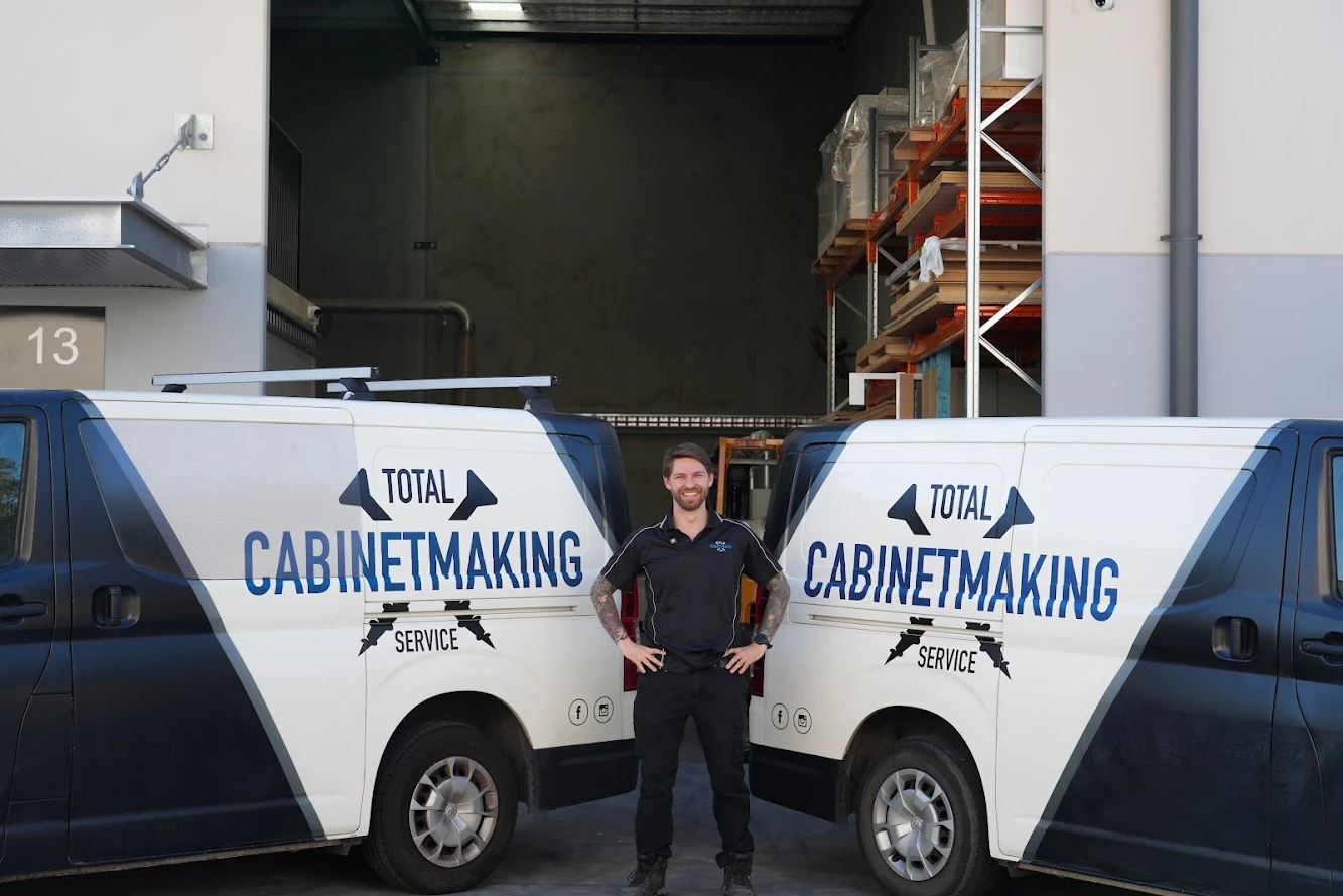 Todd Staunton standing between his two branded TCS vans outside the workshop